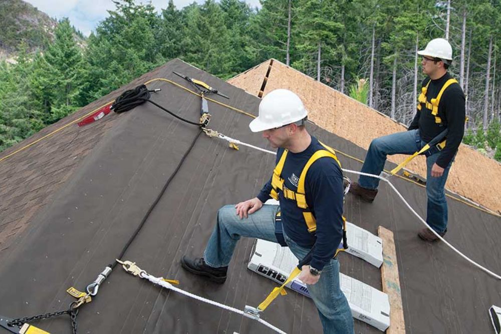 Two men in safety gear and ropes perform roofing work, showcasing a professional roofing service in San Antonio.