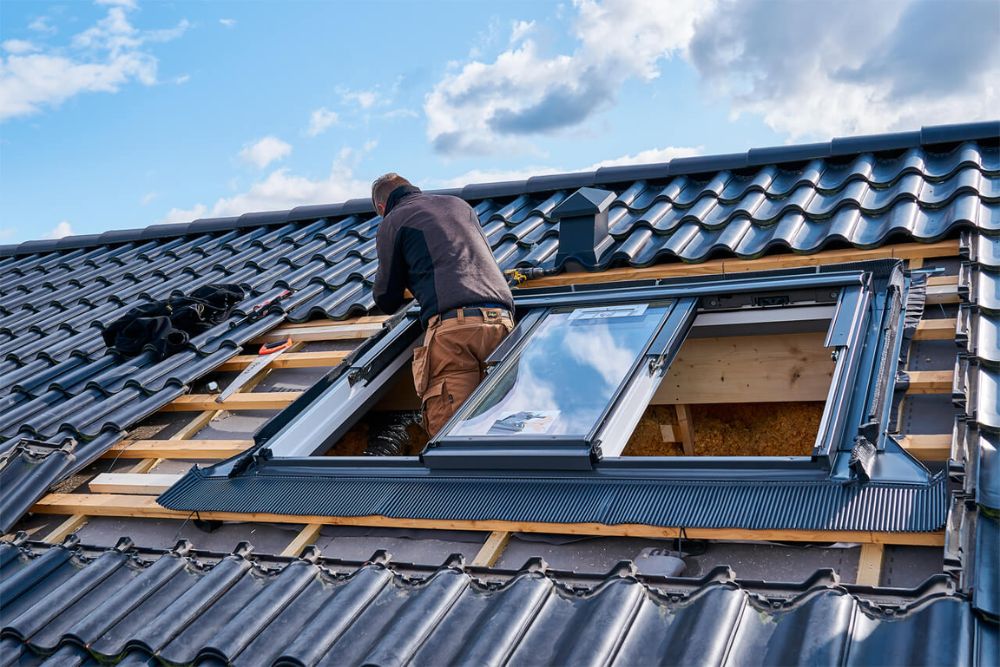A skilled worker installs a window on a roof, highlighting skylight services available in San Antonio.