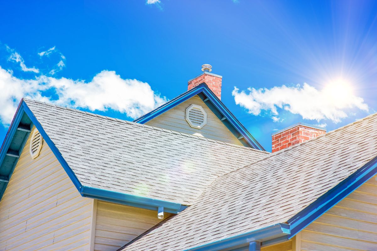 A house featuring a sloped roof and a chimney, set against a clear blue sky.