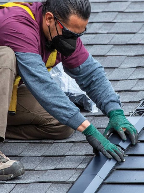 A masked man in gloves performs roofing work, showcasing a roofing service in San Antonio.
